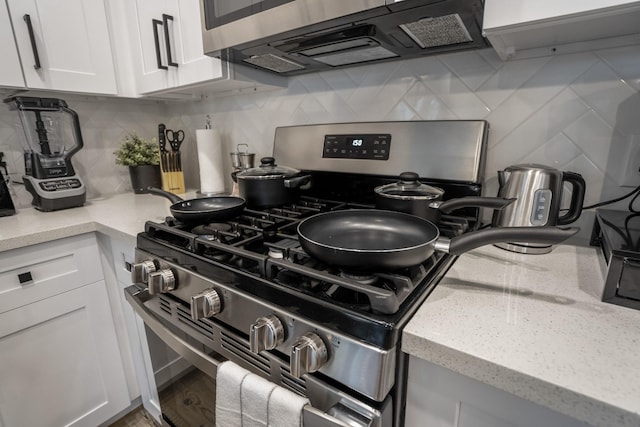 3710 Noah St, Houston, TX 77021 - kitchen with stainless steel range with gas stovetop, backsplash, white cabinets, and light stone countertops
