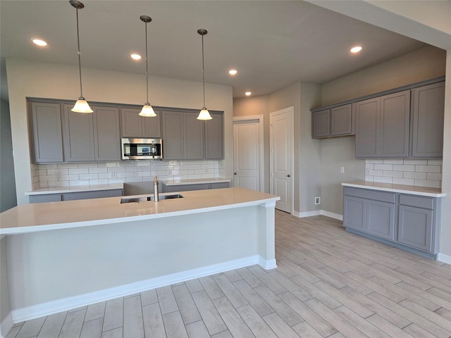 4029 Boardwalk Blvd, Seabrook, TX 77586 - kitchen featuring stainless steel microwave, a sink, gray cabinetry, decorative backsplash, and recessed lighting