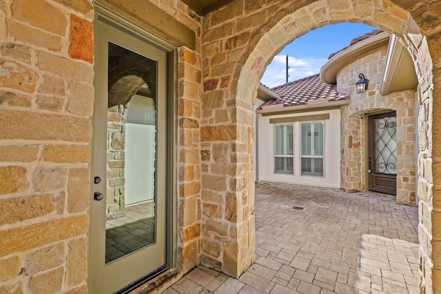 67 Quiet Vista Dr, Sugar Land, TX 77498 - doorway to property with stone siding, a tiled roof, and a patio area