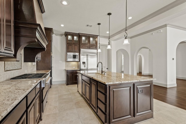 67 Quiet Vista Dr, Sugar Land, TX 77498 - kitchen featuring built in appliances, a sink, arched walkways, dark brown cabinetry, and ornamental molding