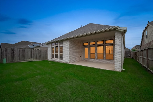 rear view of property with brick siding, a patio area, and a shingled roof