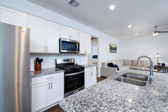 9905 Glenbrook Ln, Magnolia, TX 77354 - kitchen featuring stainless steel appliances, a sink, open floor plan, white cabinetry, and light stone counters