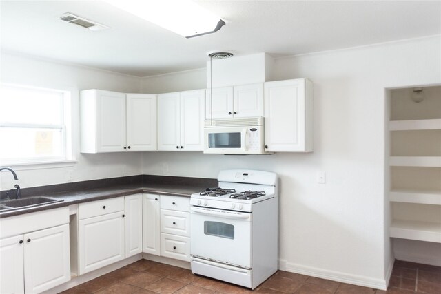 5311 Perry Ave, Galveston, TX 77551 - kitchen with white appliances, a sink, dark countertops, and white cabinetry