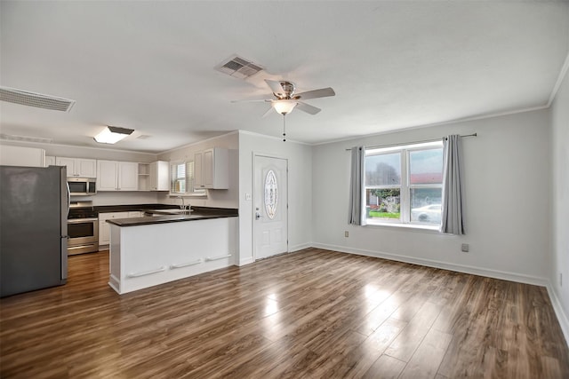 5311 Perry Ave, Galveston, TX 77551 - kitchen with stainless steel appliances, a sink, dark countertops, open shelves, and dark wood-style floors