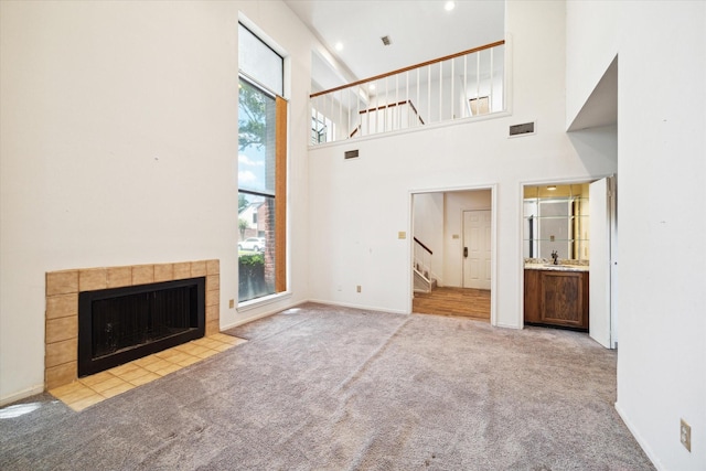 7447 Cambridge St Unit 75, Houston, TX 77054 - unfurnished living room featuring carpet, stairs, a tile fireplace, a towering ceiling, and baseboards