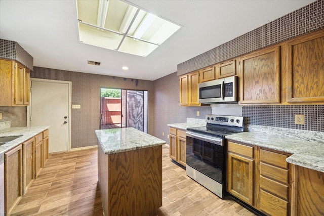 7447 Cambridge St Unit 75, Houston, TX 77054 - kitchen with appliances with stainless steel finishes, a center island, light wood finished floors, decorative backsplash, and recessed lighting