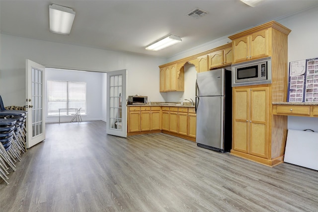 7447 Cambridge St Unit 75, Houston, TX 77054 - kitchen featuring appliances with stainless steel finishes, french doors, light wood finished floors, and light brown cabinetry