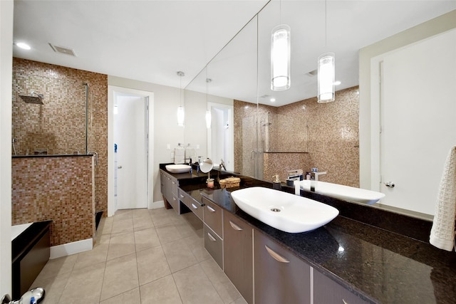 full bath with tiled shower, tile patterned flooring, vanity, and baseboards