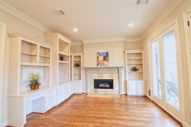 3628 Timberside Circle Dr, Houston, TX 77025 - unfurnished living room with healthy amount of natural light, light wood-style flooring, crown molding, a tiled fireplace, and built in features