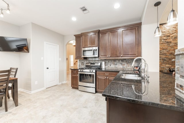19315 S Cottonwood Green Ln, Cypress, TX 77433 - kitchen featuring appliances with stainless steel finishes, a sink, tasteful backsplash, dark stone countertops, and arched walkways