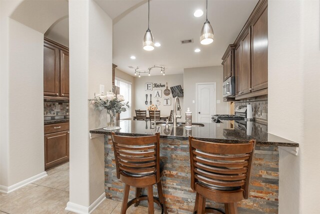 19315 S Cottonwood Green Ln, Cypress, TX 77433 - bar with stainless steel appliances, decorative backsplash, a sink, arched walkways, and light tile patterned flooring