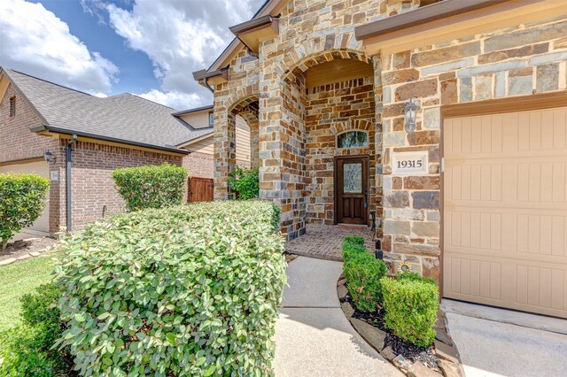 19315 S Cottonwood Green Ln, Cypress, TX 77433 - view of exterior entry featuring stone siding, a garage, brick siding, and roof with shingles