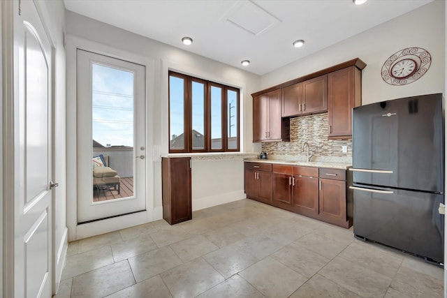 2010 Sabine St, Houston, TX 77007 - kitchen featuring freestanding refrigerator, a sink, tasteful backsplash, baseboards, and light stone countertops