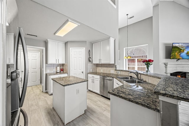 kitchen featuring a sink, appliances with stainless steel finishes, a peninsula, a high ceiling, and a kitchen island