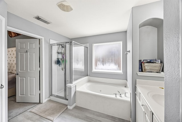 full bath featuring wood finished floors, a shower stall, a garden tub, and vanity
