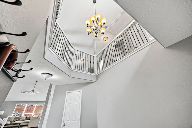 stairs with a chandelier, a towering ceiling, and ceiling fan
