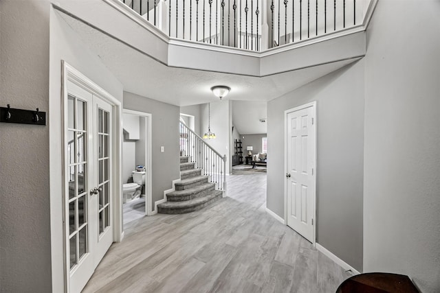 entrance foyer featuring french doors, stairway, wood finished floors, and baseboards