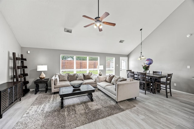 living room featuring high vaulted ceiling, ceiling fan, light wood-style floors, and baseboards
