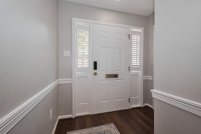 entrance foyer featuring dark wood-style flooring, a textured wall, and baseboards