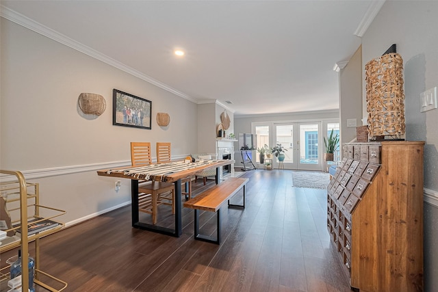 dining space with a fireplace, dark wood finished floors, crown molding, and baseboards