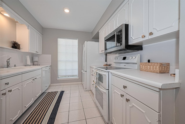 kitchen with white appliances, white cabinets, a sink, light countertops, and recessed lighting