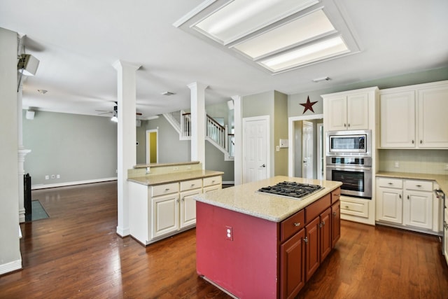 4011 N Water Iris Ct, Houston, TX 77059 - kitchen featuring appliances with stainless steel finishes, dark wood finished floors, a ceiling fan, decorative columns, and a center island