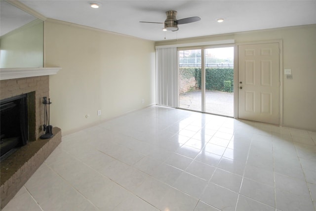 unfurnished living room featuring ceiling fan, a brick fireplace, tile patterned flooring, baseboards, and crown molding