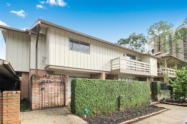 view of front of home featuring brick siding and a balcony