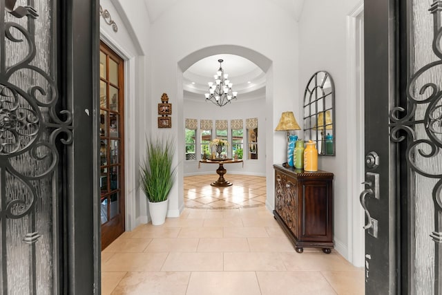 9436 Hufsmith Rd, Tomball, TX 77375 - entrance foyer with crown molding, a chandelier, arched walkways, baseboards, and light tile patterned floors