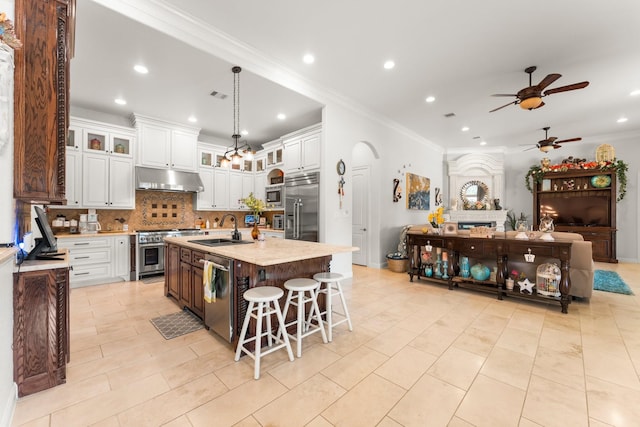 9436 Hufsmith Rd, Tomball, TX 77375 - kitchen with built in appliances, a sink, ceiling fan, under cabinet range hood, and decorative backsplash