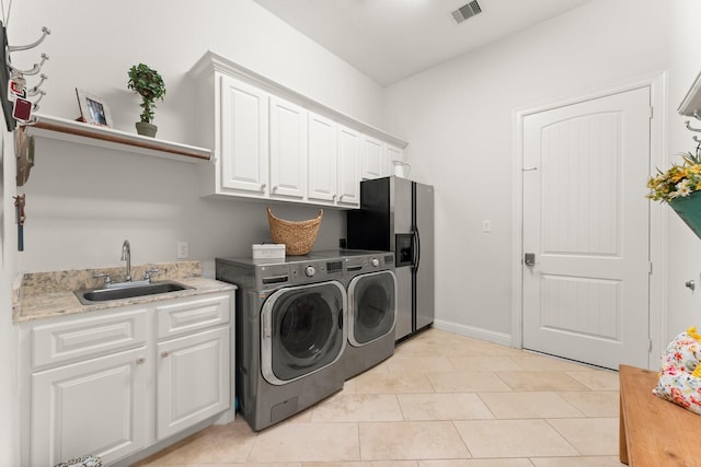 9436 Hufsmith Rd, Tomball, TX 77375 - laundry room featuring washer and dryer, cabinet space, and light tile patterned floors