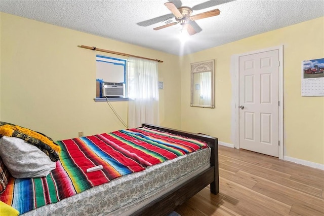 1927 Dormstom Ln, Houston, TX 77088 - bedroom featuring wood finished floors, a textured ceiling, cooling unit, baseboards, and a ceiling fan