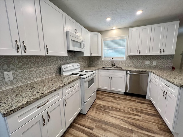 1705 Westwind Dr, Brenham, TX 77833 - kitchen featuring white appliances, a sink, white cabinetry, light stone counters, and tasteful backsplash
