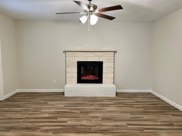 1705 Westwind Dr, Brenham, TX 77833 - unfurnished living room featuring wood finished floors, a ceiling fan, baseboards, a glass covered fireplace, and a textured ceiling