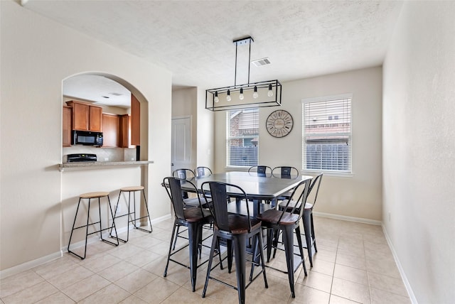 13602 Kodiak Brown Bear St, Crosby, TX 77532 - dining area with arched walkways, light tile patterned floors, a textured ceiling, and baseboards