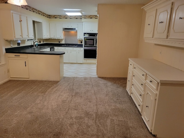 209 Montclaire Dr, West Columbia, TX 77486 - kitchen with gas stovetop, a peninsula, under cabinet range hood, light colored carpet, and dark countertops