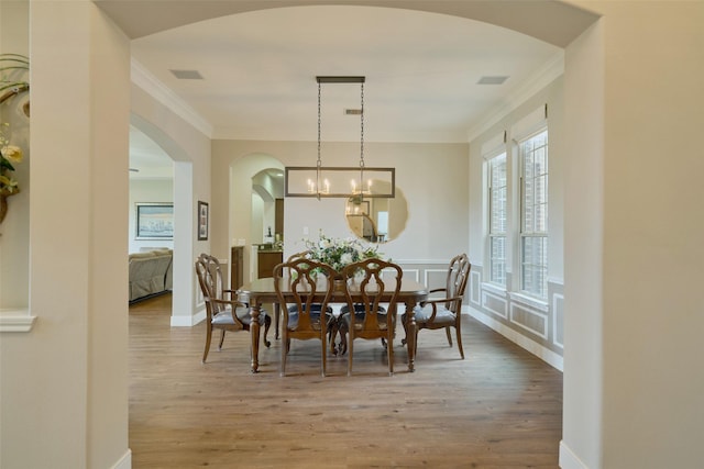 13606 Oak Harbor Bnd, Cypress, TX 77429 - dining space featuring arched walkways, wood finished floors, ornamental molding, baseboards, and a chandelier