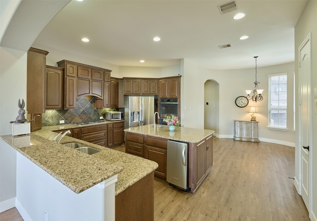 13606 Oak Harbor Bnd, Cypress, TX 77429 - kitchen featuring arched walkways, a sink, stainless steel appliances, a peninsula, and backsplash