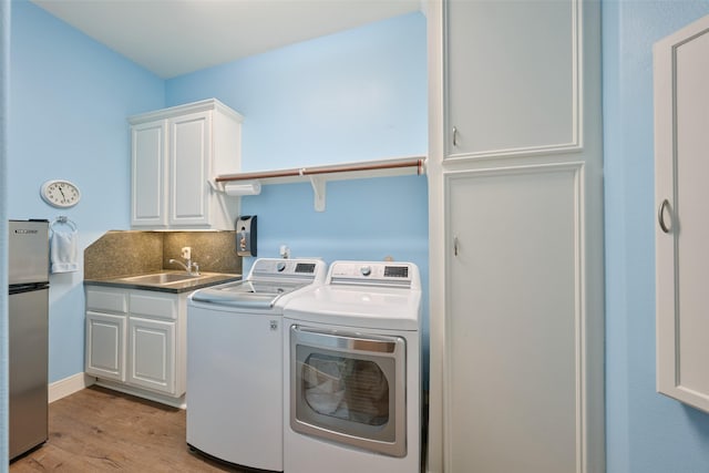 13606 Oak Harbor Bnd, Cypress, TX 77429 - washroom with washer and dryer, cabinet space, and light wood-style floors