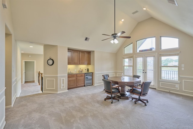 13606 Oak Harbor Bnd, Cypress, TX 77429 - dining room with a decorative wall, high vaulted ceiling, bar with sink, beverage cooler, and wainscoting
