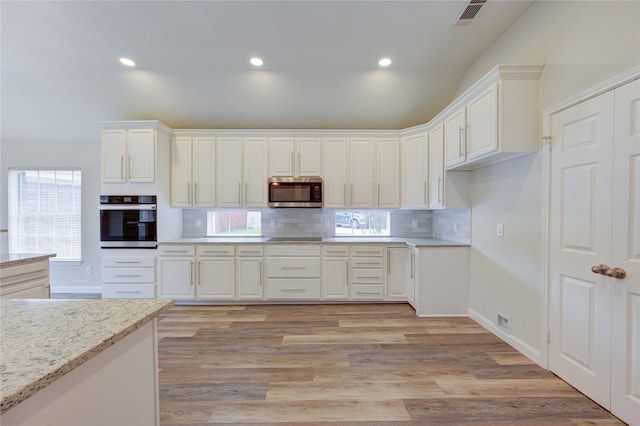 12507 Antean Way Ct, Houston, TX 77065 - kitchen featuring appliances with stainless steel finishes, backsplash, white cabinetry, light stone countertops, and light wood-style flooring