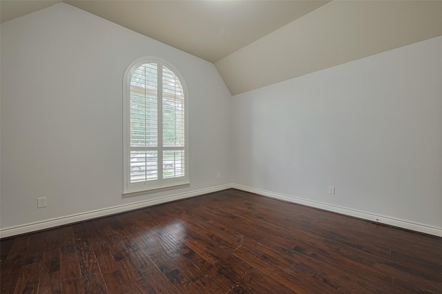unfurnished room with vaulted ceiling, dark wood-type flooring, and baseboards