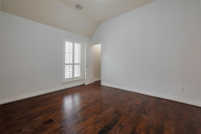empty room featuring vaulted ceiling, dark wood-style floors, and baseboards