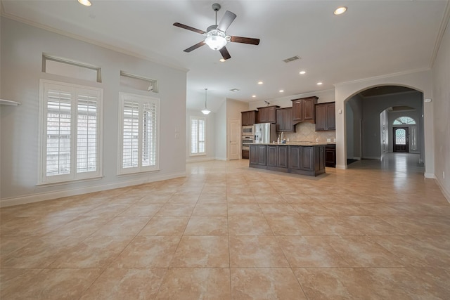 unfurnished living room featuring crown molding, a ceiling fan, arched walkways, baseboards, and light tile patterned floors