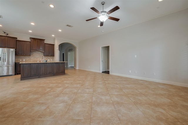kitchen featuring stainless steel fridge, crown molding, arched walkways, a ceiling fan, and open floor plan