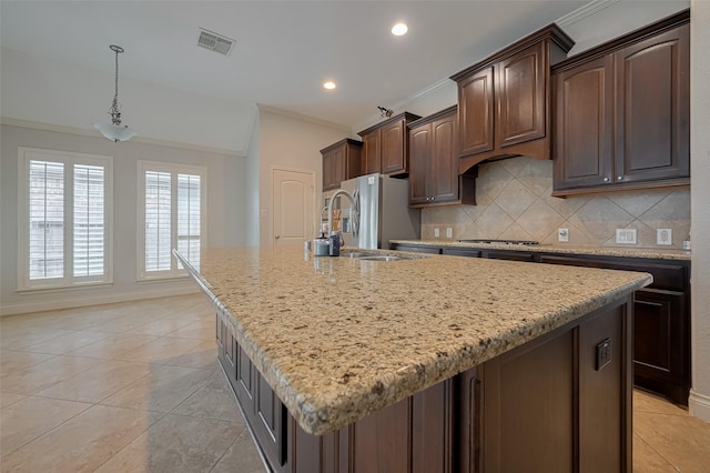 kitchen featuring ornamental molding, backsplash, a kitchen island with sink, light tile patterned floors, and stainless steel appliances