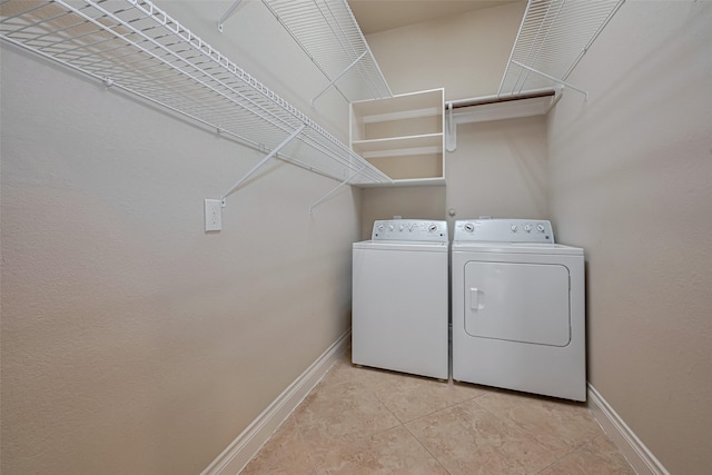 laundry area with washer and clothes dryer, baseboards, and light tile patterned floors