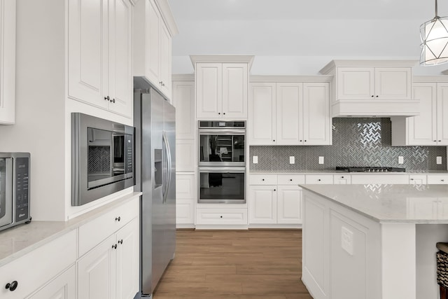 1827 Woodtrace Blvd, Pinehurst, TX 77362 - kitchen with appliances with stainless steel finishes, tasteful backsplash, wood finished floors, white cabinets, and hanging light fixtures