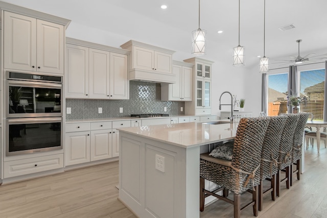 1827 Woodtrace Blvd, Pinehurst, TX 77362 - kitchen with a sink, appliances with stainless steel finishes, light wood-style floors, tasteful backsplash, and light countertops