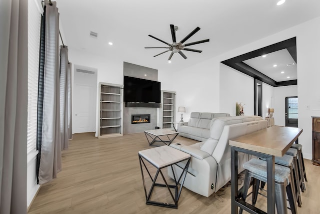1827 Woodtrace Blvd, Pinehurst, TX 77362 - living area with a glass covered fireplace, light wood-style flooring, ceiling fan, and recessed lighting